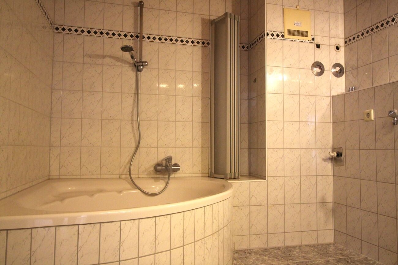 Das zeitlose Badezimmer besitzt sowohl eine Duschbadewanne...