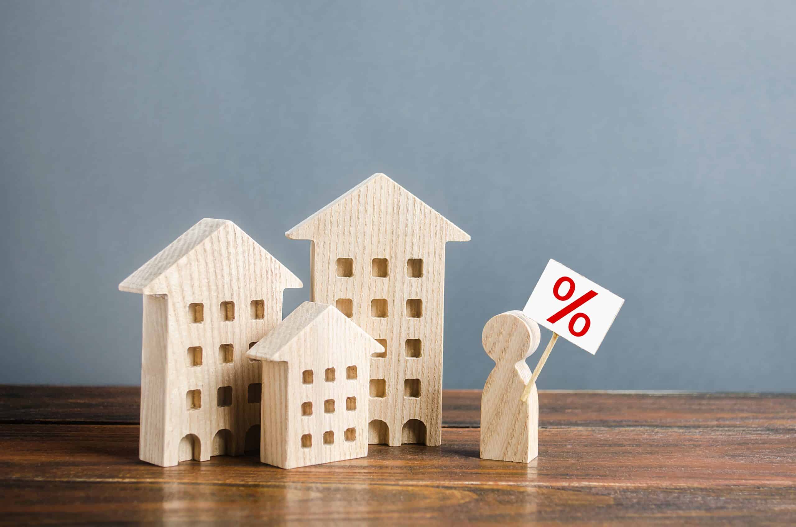 A person with a poster is standing near the houses. Mortgage to purchase affordable comfortable housing. Concessional lending programs for young families. Low rates attractive real estate propositions
